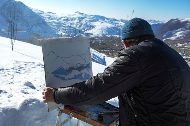 El artista pinta un paisaje de montaña.