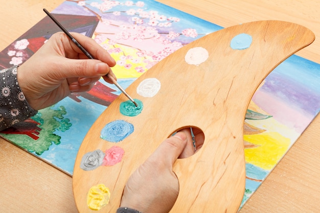 Artista pintando paisagens japonesas em ambientes internos na mesa de madeira com paleta