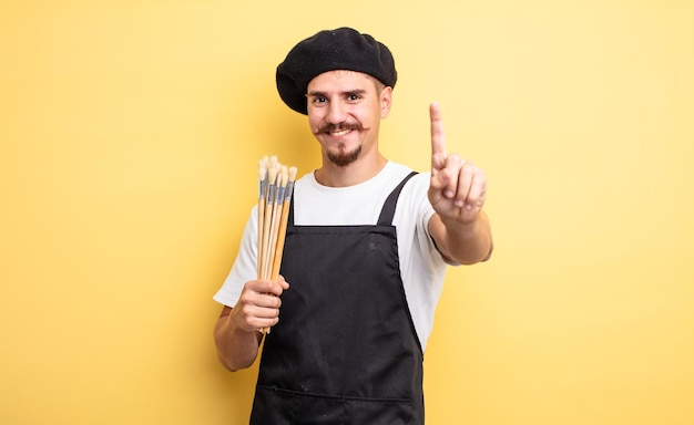 Artista pintor sonriendo con orgullo y confianza haciendo el número uno