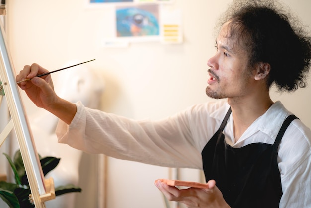 Artista de pintura joven asiático masculino que trabaja en el estudio, estilo de vida de la afición del arte en casa