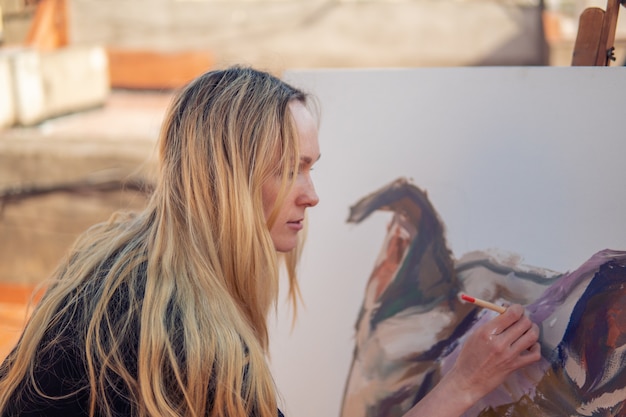 Foto artista de pintura joven dibujando en el techo de su casa. cuadro de bulldog sobre lienzo grande. arte al aire libre