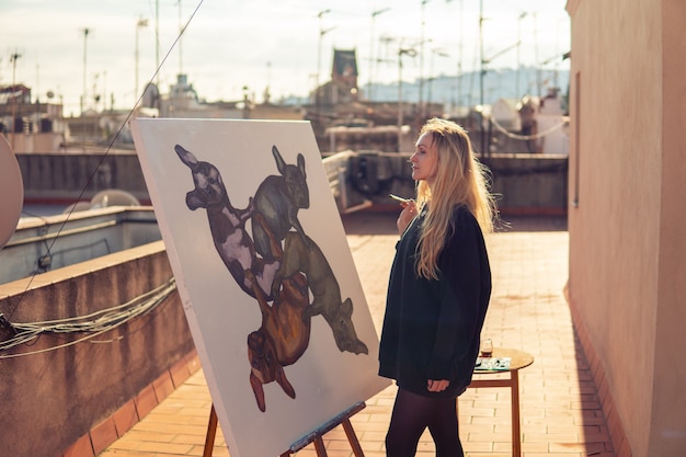 Artista de pintura joven dibujando en el techo de su casa. Cuadro de bulldog sobre lienzo grande. Arte al aire libre