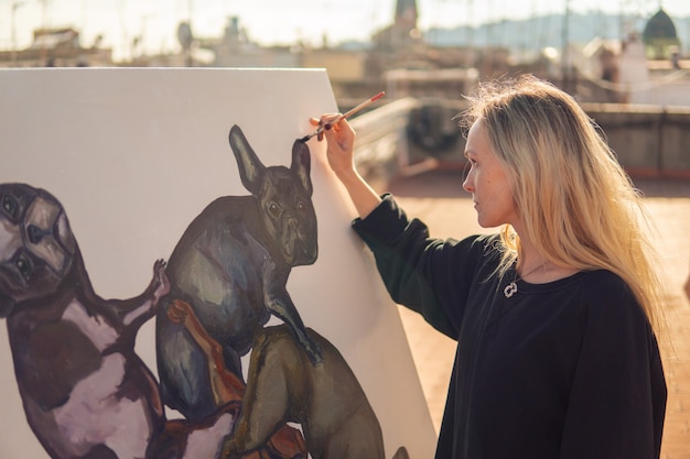 Artista de pintura joven dibujando en el techo de su casa. Cuadro de bulldog sobre lienzo grande. Arte al aire libre