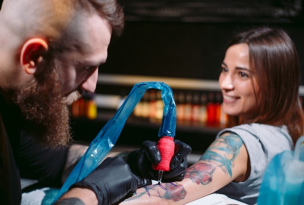 El artista profesional del tatuaje hace un tatuaje en la mano de una niña.