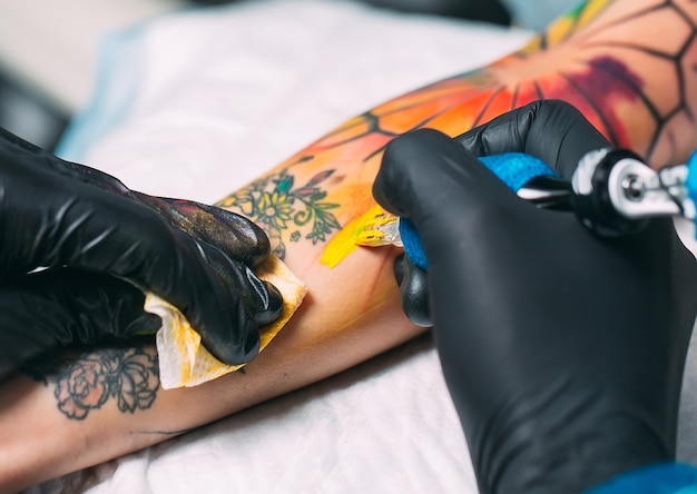 El artista profesional del tatuaje hace un tatuaje en la mano de una niña.