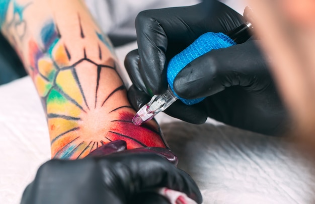 El artista profesional del tatuaje hace un tatuaje en la mano de una niña.