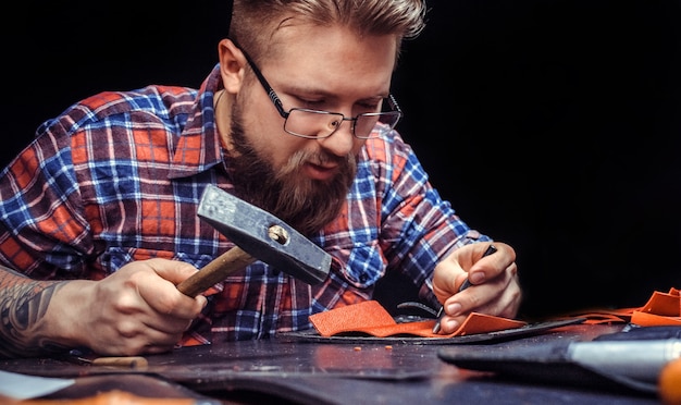 Artista que trabaja con cuero creando marroquinería en la tienda de curtidores