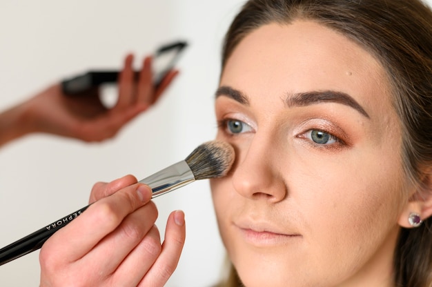 El artista del retrato de maquillaje de boda de cerca trabaja con un pincel en la cara de las novias