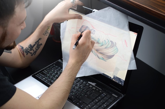 Foto el artista rodea el boceto a pluma de un tatuaje en el escritorio