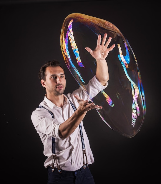 Foto artista segura grande bolha de sabão em suas mãos conceito de estúdio de show de bolhas