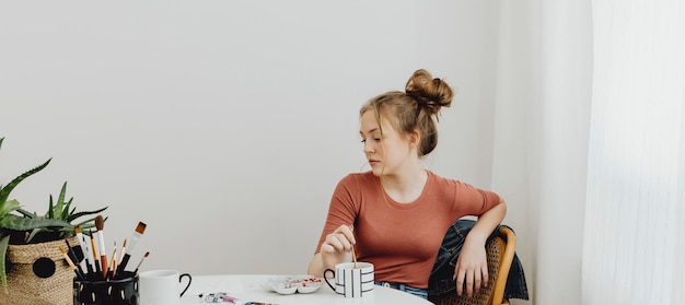 Artista sentada pensativamente enquanto olha para sua obra de arte