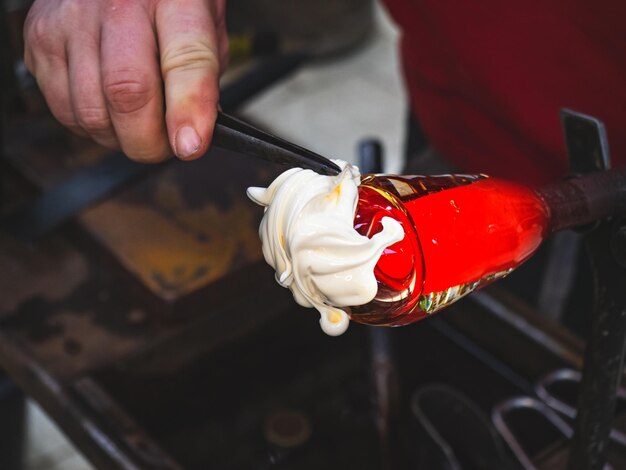 Foto artista soplador de vidrio crea una capa blanca hombre trabajando con vidrio caliente para hacer una pieza de arte de vidrio soplado