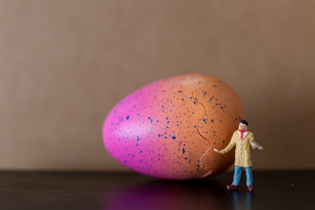 Foto artista sostiene un pincel y pinta huevos de pascua.