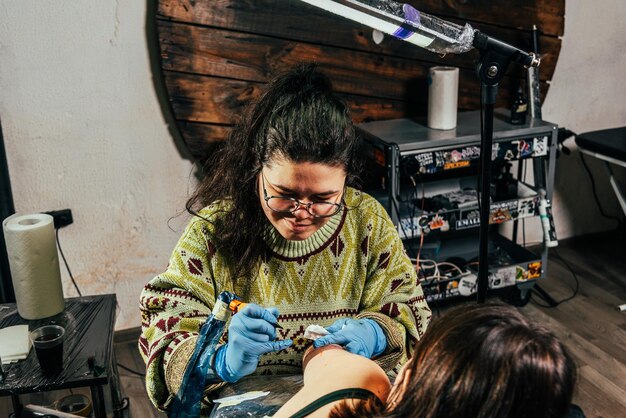 Un artista del tatuaje hace un tatuaje en un salón.