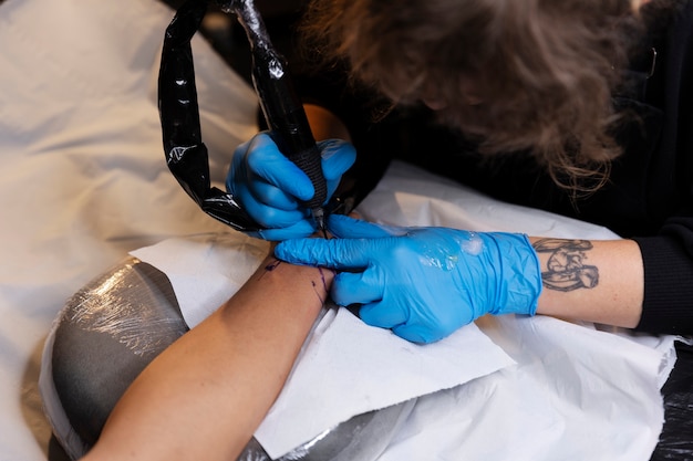 Foto artista del tatuaje haciendo su trabajo de alto ángulo