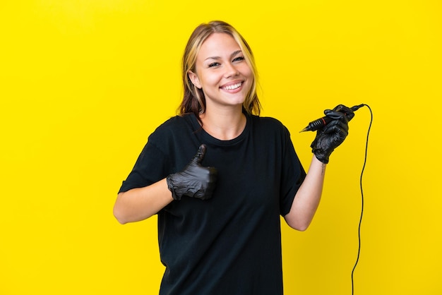 Artista del tatuaje mujer rusa aislada sobre fondo amarillo dando un pulgar hacia arriba gesto