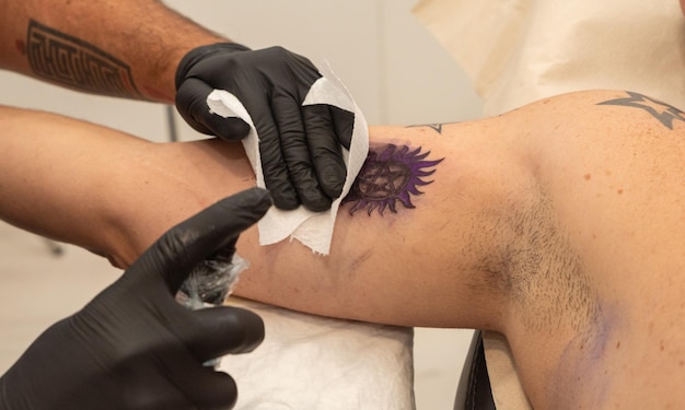 Foto artista del tatuaje realizando un tatuaje en un cliente