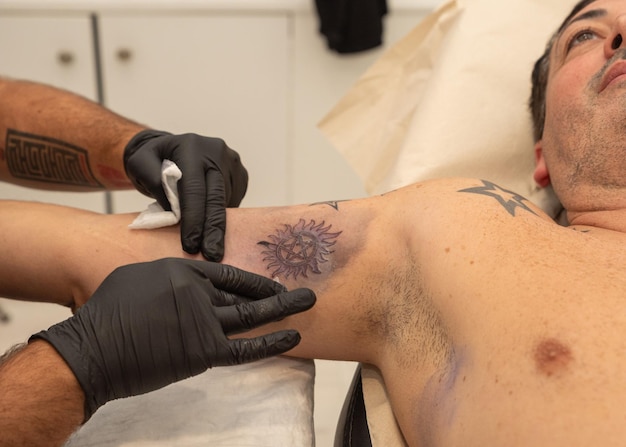 Foto artista del tatuaje realizando un tatuaje en un cliente