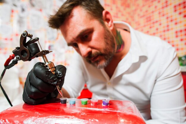 Artista del tatuaje rellenando la pistola con tinta