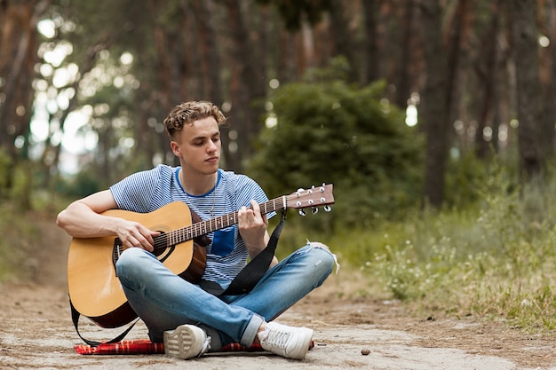 artista tocando la guitarra en el bosque. bardo senderismo y estilo de vida viajero.