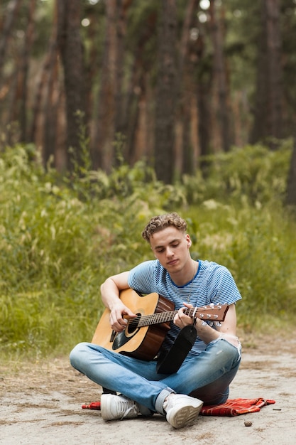 artista tocando la guitarra en el bosque. bardo senderismo y estilo de vida viajero.