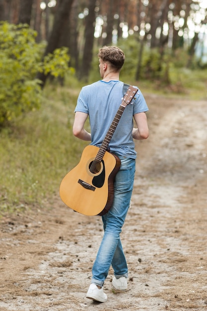 artista tocando la guitarra en el bosque. bardo senderismo y estilo de vida viajero.