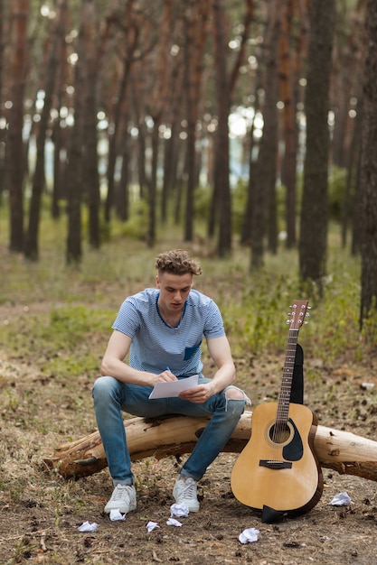 artista tocando guitarra na floresta. caminhada barda e estilo de vida do viajante