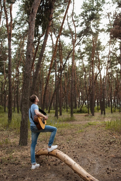 Foto artista tocando guitarra na floresta. caminhada barda e estilo de vida do viajante