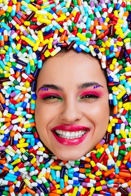 Foto artística una hermosa mujer hundida dentro de píldoras y cápsulas de colores.