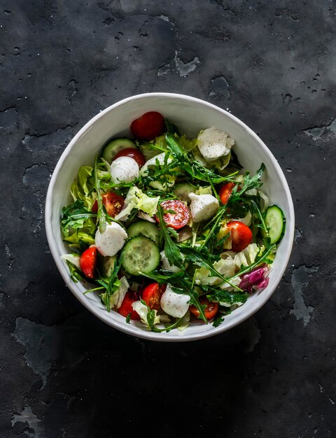 Arugula cherry tomates pepinos salada de queijo mozzarella com molho de mostarda de limão em um fundo escuro vista de cima