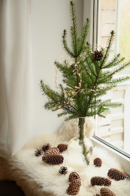 Foto Árvore de natal alternativa de ramos naturais em um vaso no parapeito da janela aconchegante fim de semana