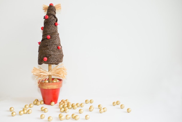 Foto Árvore de natal artesanal e pequenas bolas douradas com fundo branco