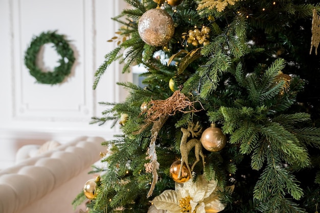 Árvore de natal com bolota vintage e enfeites com luzes douradas fecham galhos de árvores de natal decoradas modernas com ornamentos elegantes na sala festiva férias de inverno tempo atmosférico