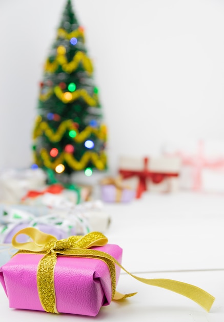 Árvore de Natal com decoração e presentes em um fundo branco de madeira