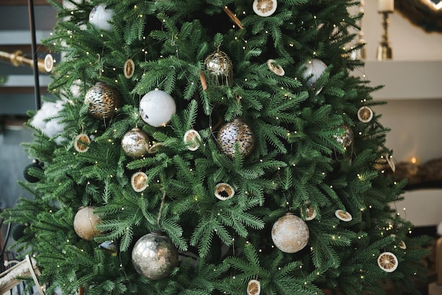 Árvore de natal com enfeites e luzes de fadas. fundo de natal. feche de enfeites de natal na árvore. árvore de natal na cor branca e dourada.