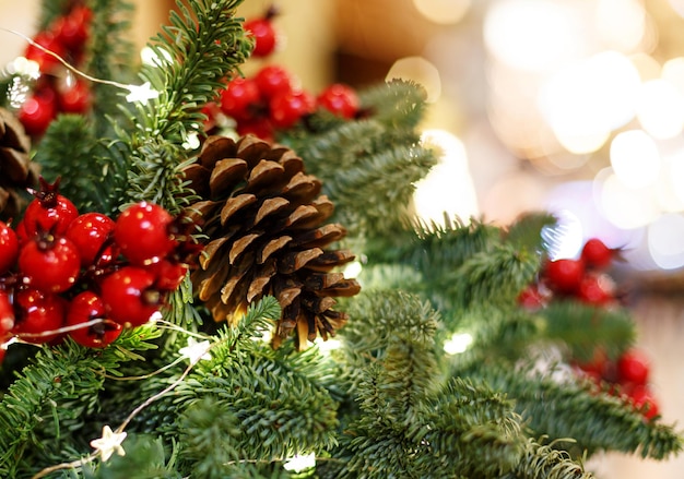 Árvore de natal com frutas vermelhas e cones. fundo de celebração de ano novo de conceito. foto do close up da árvore de natal decorada com cones e bagas vermelhas. cartão de ano novo