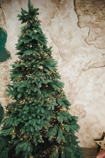 Árvore de natal com guirlandas. árvore de natal com brinquedos em um fundo de parede retrô marrom