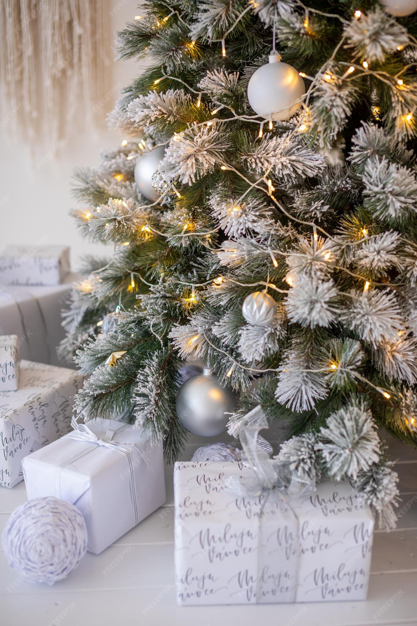 Árvore de natal com neve branca com decoração de presentes no interior da  casa de ano novo