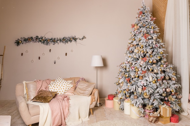 Árvore de natal com presentes. decoração de férias. árvore de natal elegante com brinquedos brancos e rosa nos apartamentos de luxo. árvore lindamente decorada com enfeites rosa, fitas, flocos de neve