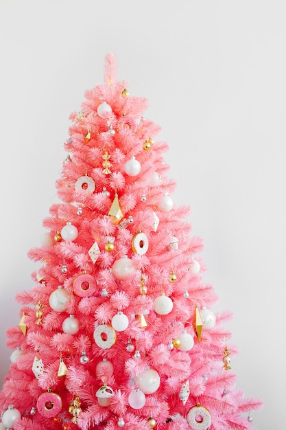 Foto Árvore de natal cor-de-rosa e decorações de natal brancas e douradas. fundo de natal. feliz ano novo e conceito de natal de natal.