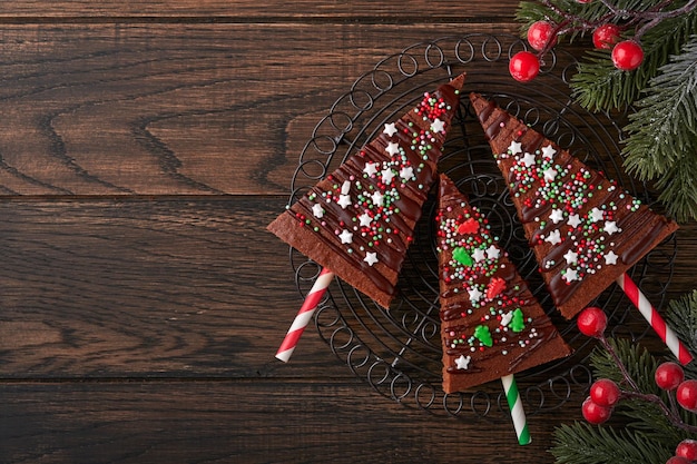 Árvore de natal de brownies de chocolate com cobertura de chocolate e granulado festivo na mesa de madeira idéias de comida de natal doce conceito de pastelaria caseira de natal conceito de culinária de férias vista superior