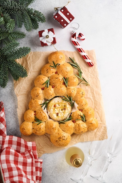 Árvore de natal de pães de pão com queijo camembert assado e alecrim em fundo rústico. receitas de férias. cardápio de natal. doces de natal ou natal. vista do topo. copie o espaço.