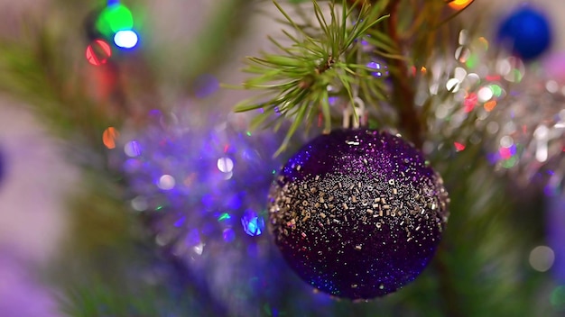 Árvore de natal decorada com bola de vidro azul no galho de abeto de natal no fundo bokeh de lâmpadas piscando guirlandas