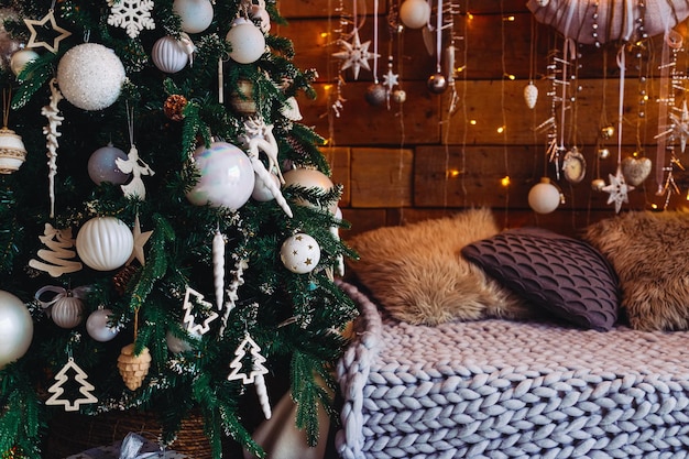 Árvore de natal decorada com branco e brinquedos e um sofá com uma manta e travesseiros ambiente aconchegante