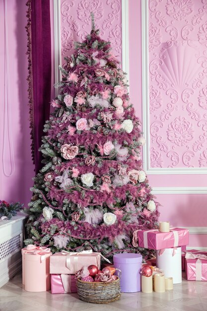 Árvore de natal decorada com brinquedos cor de rosa. fundo de natal com presentes no interior da sala