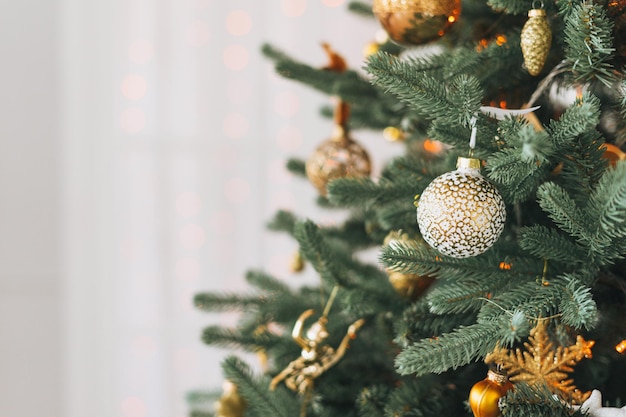 Árvore de natal decorada em brinquedos dourados e brancos com fundo texturizado de boque de luzes