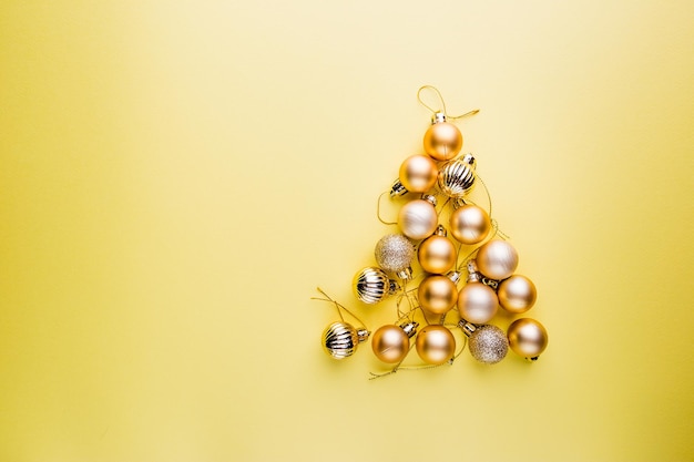 Árvore de natal feita de bolas de natal em fundo amarelo. banner de ano novo com estilo mínimo.