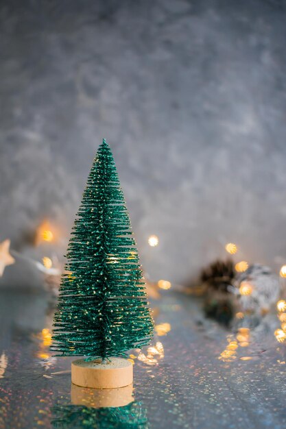 Árvore de Natal fofa decorativa sobre um fundo cinza com luzes desfocadas. Fundo de Natal. Copie o espaço. Visão vertical