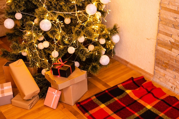 Árvore de natal iluminada com presentes embaixo na sala de estar