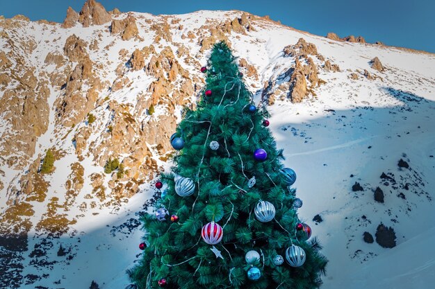 Árvore de natal na floresta de neve da montanha. árvore de natal decorada com grandes bolas no fundo das montanhas.